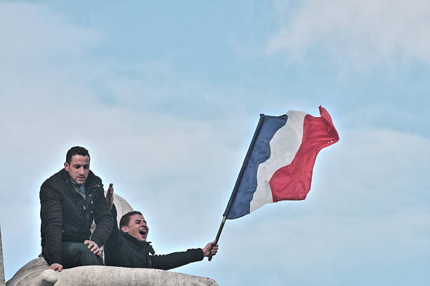 Paris, France - January 11, 2015: Man waving french flag during manifestation on Republic Square in Paris against terrorism and in memory of the attack against satirical newspaper Charlie Hebdo.