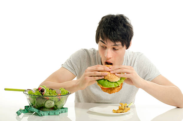istock Man holding in front a bowl of salad and hamburger 535116471