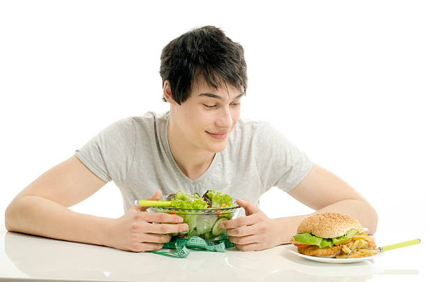 istock Man holding in front a bowl of salad and hamburger 535117235