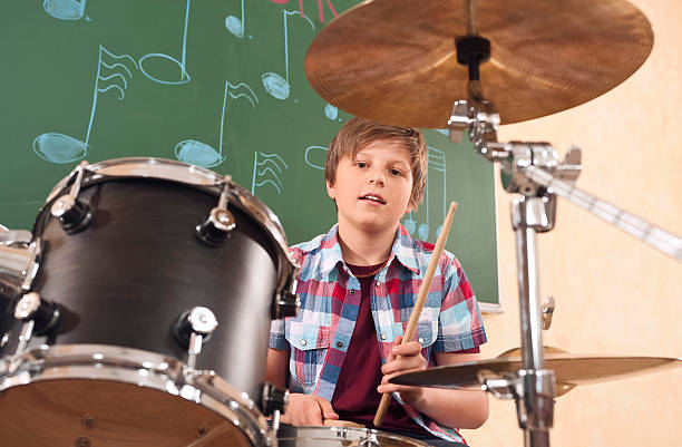 Boy playing drums at music class stock photo