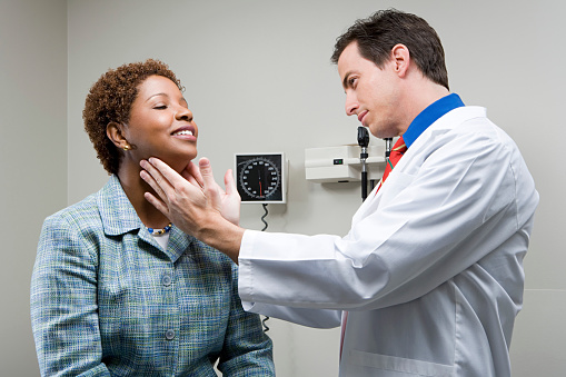 Doctor checking woman's throat