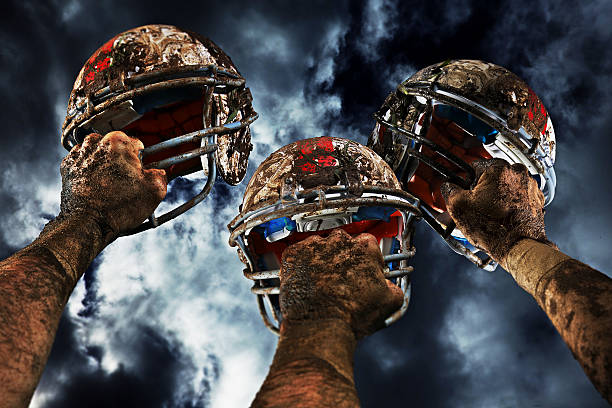 American football players kneeling on the field with helmets, showing respect