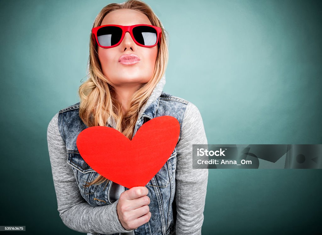 Teen girl in love Portrait of cute teen girl with red paper heart isolated on gray background, kiss with love, Valentine day, affection concept 2015 Stock Photo