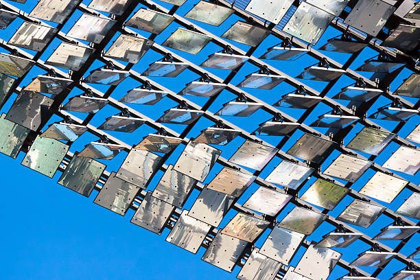 Low angle view of Heliostat against blue sky, copy space Closeup low angle view of heliostat of motorised mirrors with sunlight reflection on high rise building Sydney Australia, full frame horizontal composition background with copy space concentrated solar power photos stock pictures, royalty-free photos & images