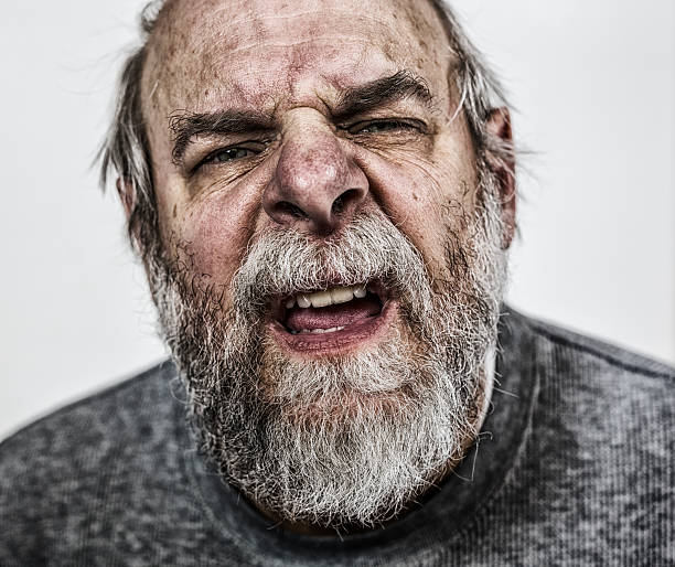Confused Senior Adult Man Close-up Close-up of a grubby senior adult gray beard man peering at the camera with squinty eyes and his face wrinkled up in curiosity or confusion. Toned image. confusion raised eyebrows human face men stock pictures, royalty-free photos & images