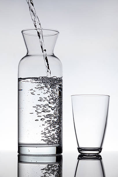 пустой стакан и бутылка в форме графина, наполненную водой - wine decanter elegance pouring стоковые фото и изображения