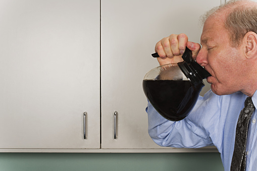 Businessman drinking out of coffee pot