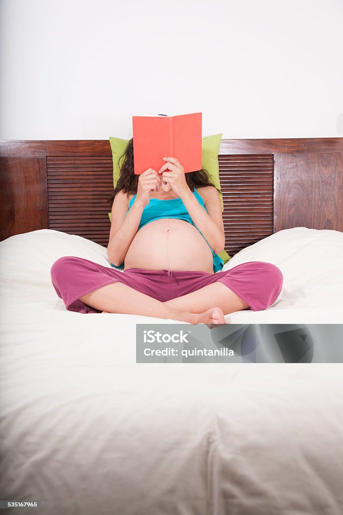 pregnant reading sitting in bed pregnant woman reading a book sitting in bed Book Stock Photo