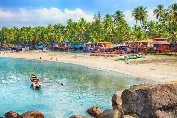 Beautiful Goa province beach in India with fishing boats and stones in the sea 