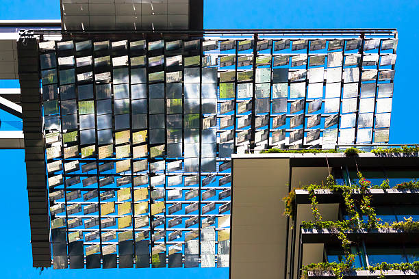 Low angle view of Heliostat motorised mirrors against blue sky Low angle view of heliostat of motorised mirrors on high rise building against blue sky Sydney Australia, full frame horizontal composition background concentrated solar power photos stock pictures, royalty-free photos & images