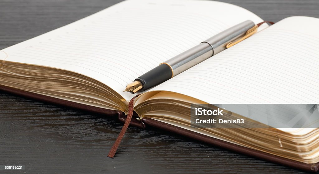 notebook on the table Opened notebook and a pen lying on a wooden table 2015 Stock Photo