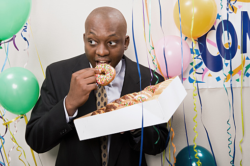 Businessman secretly eating doughnuts