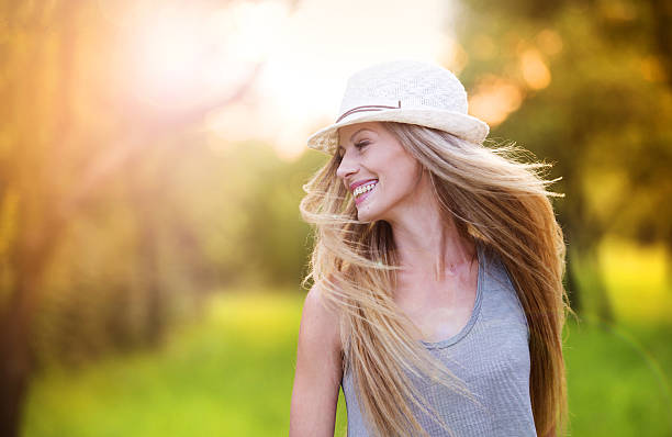 Beautiful woman outside in a park. Attractive young woman enjoying her time outside in park with sunset in background. blonde model in dress stock pictures, royalty-free photos & images