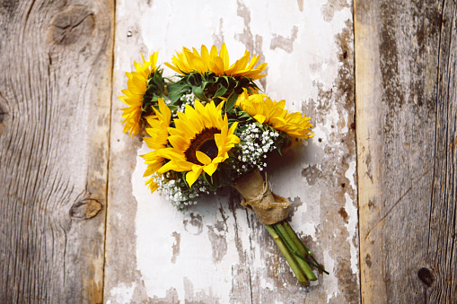 A beautiful sunflower wedding bouquet, laying on rustic barn board. High angle shot with copy space. 