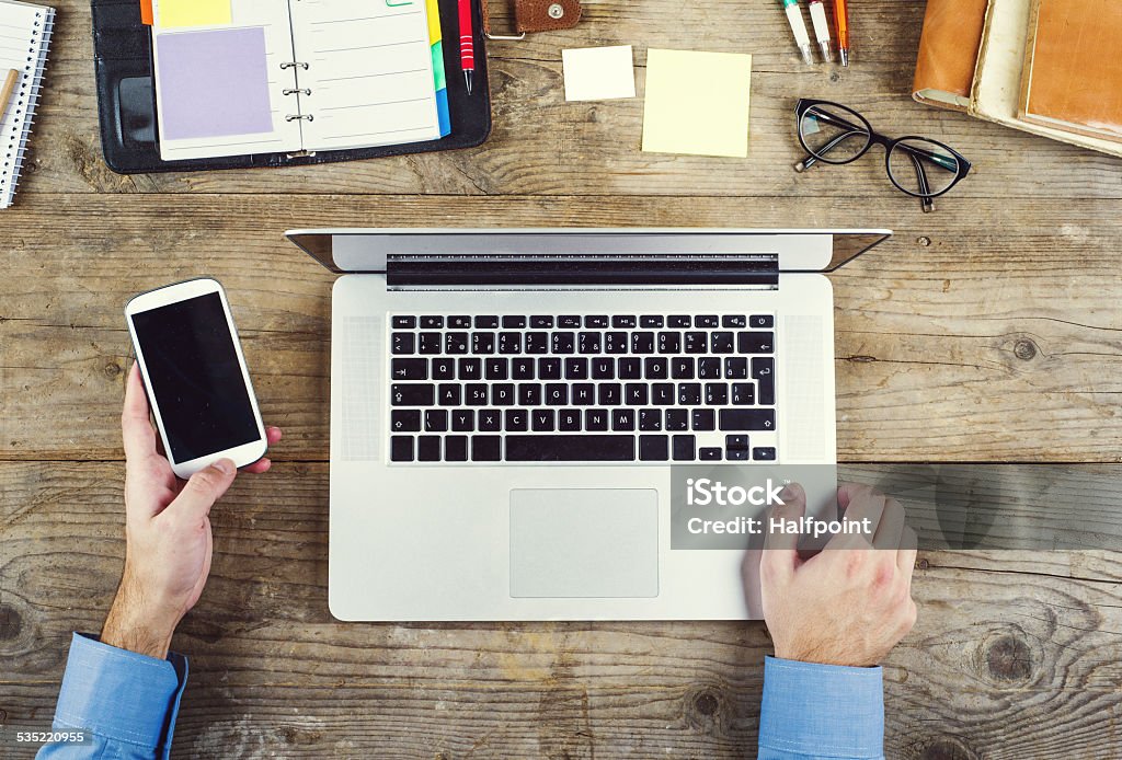 Desktop mix on a wooden office table. Mix of office supplies and gadgets on a wooden table background. View from above. 2015 Stock Photo