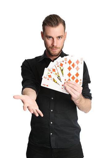 Young and attractive man wearing a black shirt with his sleeves rolled up, holding a fan of a royal flush in diamonds on big sized cards. White background.