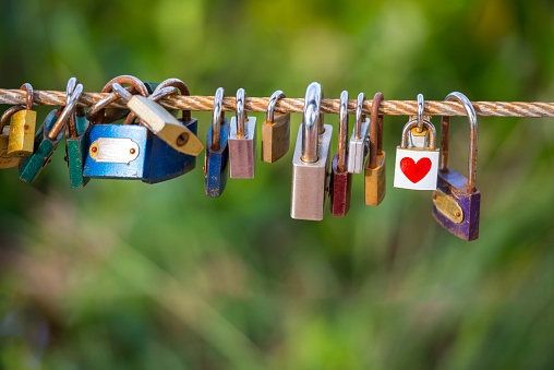 Padlocks hanging on the metal with heart shape on rope bridge