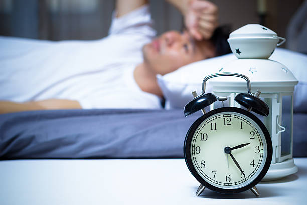 Asian man in bed suffering insomnia and sleep disorder stock photo