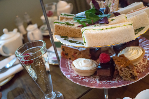 A posh afternoon tea of Champagne, sandwiches and cakes - selective focus