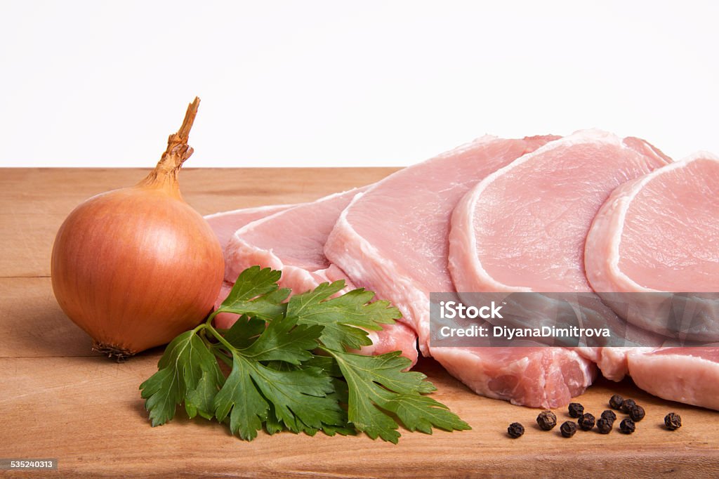 Raw pork meat, vegetables and spices, arranged on kitchen board Raw pork meat, vegetables and spices, arranged on kitchen board - selective focus, copy space 2015 Stock Photo