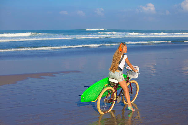 istock Young girl with surfboard and bicycle 535242591