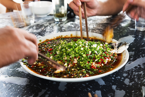 people eating chinese traditional spicy fish stew in southwest china