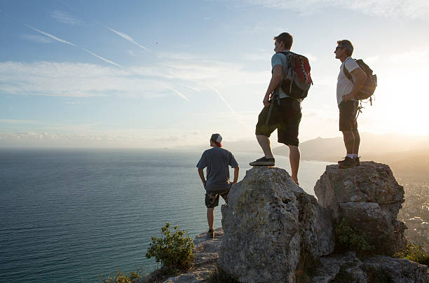 istock Three men look out to view at top of hike 535260875