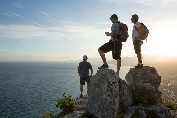 istock Three men look out to view at top of hike 535260891