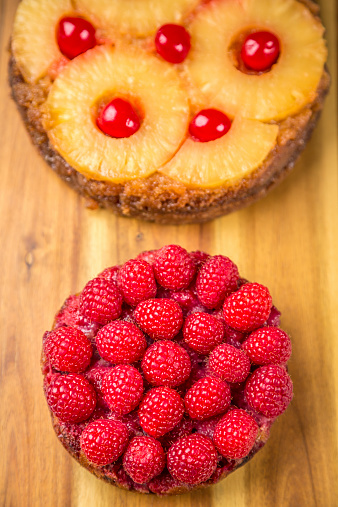 Two differents upside-down cakes with pineapple and raspberries.