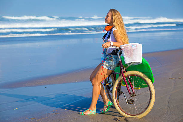 istock Young girl with surfboard and bicycle 535261319