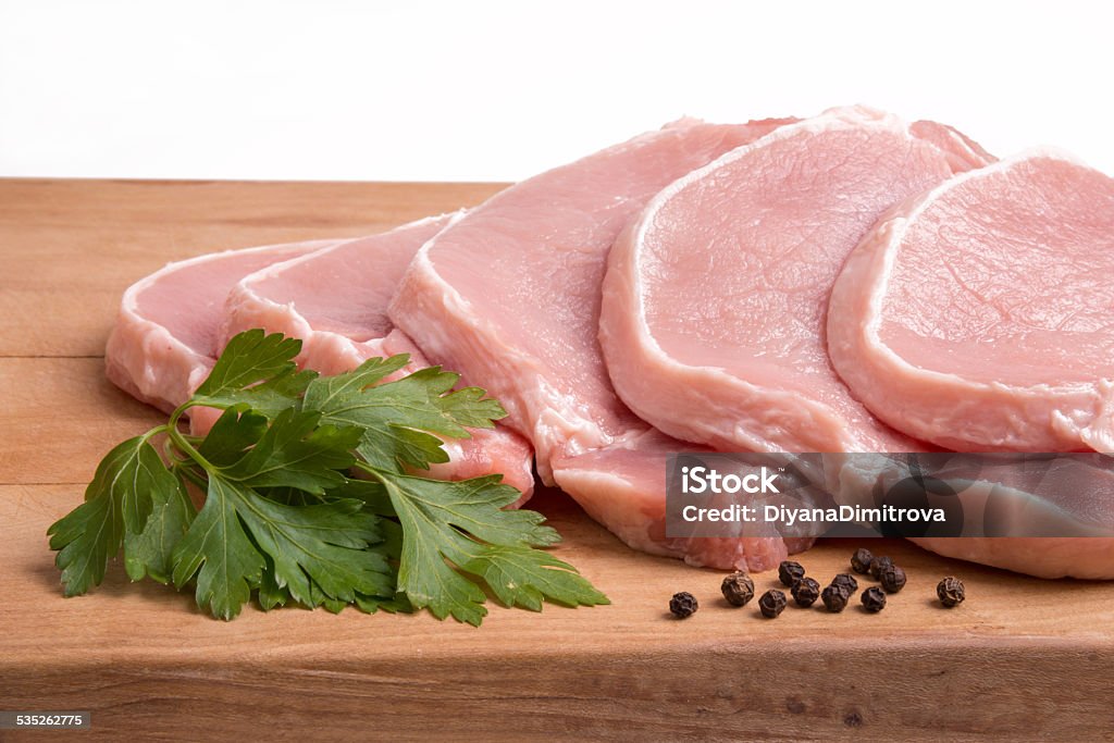 Raw pork meat, vegetables and spices, arranged on kitchen board Raw pork meat, vegetables and spices, arranged on kitchen board - selective focus, copy space 2015 Stock Photo