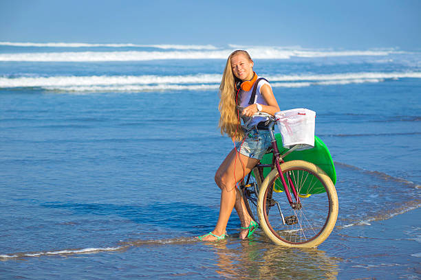 istock Young girl with surfboard and bicycle 535265243