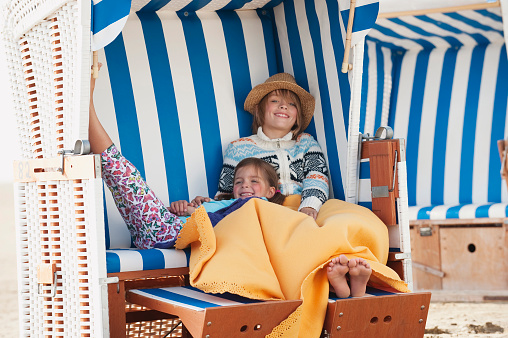 Germany, St.Peter-Ording, North Sea, Children resting on hooded beach chair