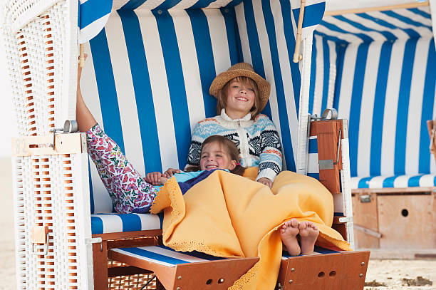Germany, St.Peter-Ording, North Sea, Children resting on hooded beach chair stock photo