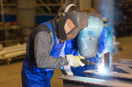 Two steel construction workers welding metal pieces