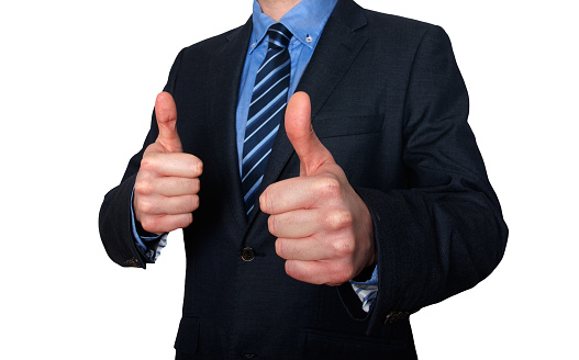 Businessman stands in front of white background and gesturing with thumbs up. Horizontal shot.