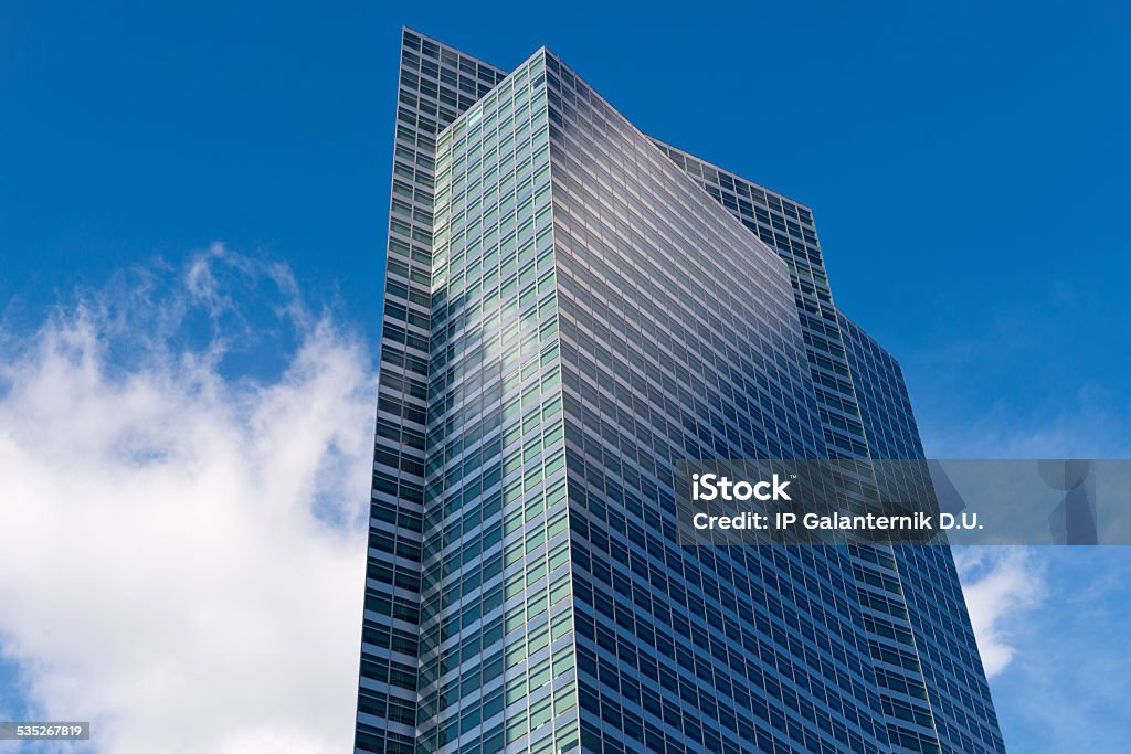 Skyscrapers from ground view with blue sky visible A low-angled daytime view of corporate skyscrapers with a deep blue sky and fluffy clouds overhead.  2015 Stock Photo