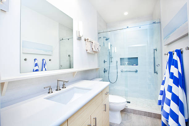 Modern Bathroom Design with Shower Stall A modern bathroom is pictured with cabinets, drawers, mirror, window, and shower stall. powder room stock pictures, royalty-free photos & images
