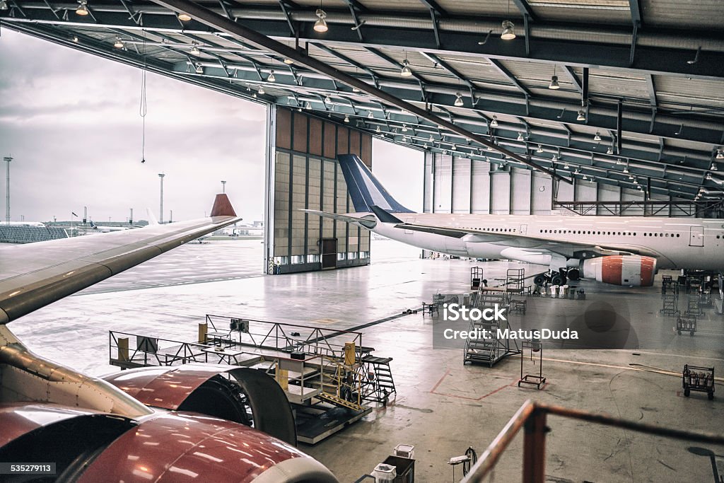 Aircrafts in hangar Two wide body aircrafts are parked and servicing in hangar. Repairing Stock Photo