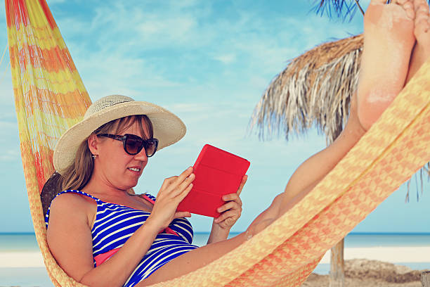 woman relaxing in hammockwith touch pad at the sea young woman relaxing in hammockwith touch pad at the sea kindle and ook stock pictures, royalty-free photos & images