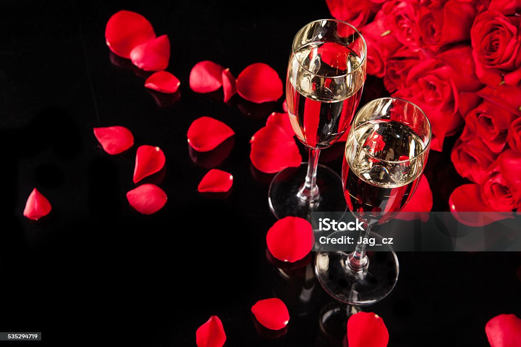 Bouquet of roses with champagne Bouquet of roses with two glasses of champagne, isolated on black background Champagne Stock Photo