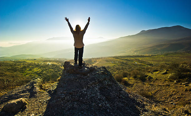 istock girl with hands up in the mountsins against sun 535294821