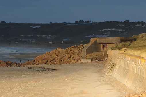 Telephoto image of a WW2 bunker and emplacement built on the beach with Anti-tank walls, lit by Winter sunlight.