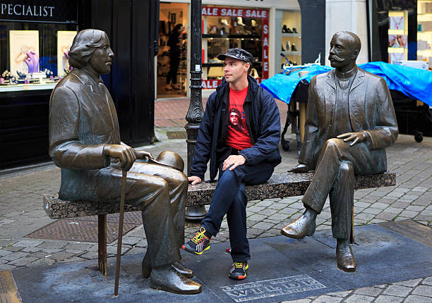 Galway, Ireland - August 26, 2014: Tourist on the bench with the Irish writer Oscar Wilde. Galway in Ireland.