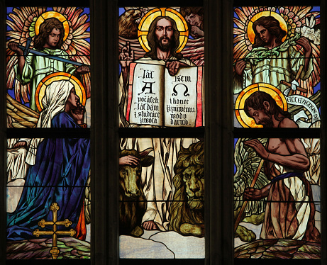 Vertical photo of the beautiful colourful stained glass window depicting Saint John the Evangelist, holding a golden goblet containing a purple dragon, with the Heraldic Eagle of St John at his feet, as seen from inside the heritage listed Saints Mary and Joseph Catholic Cathedral, Armidale, New England high country, northern NSW.