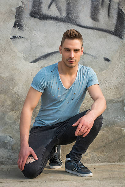 istock Handsome young man sitting on concrete with ripped jeans 535317333