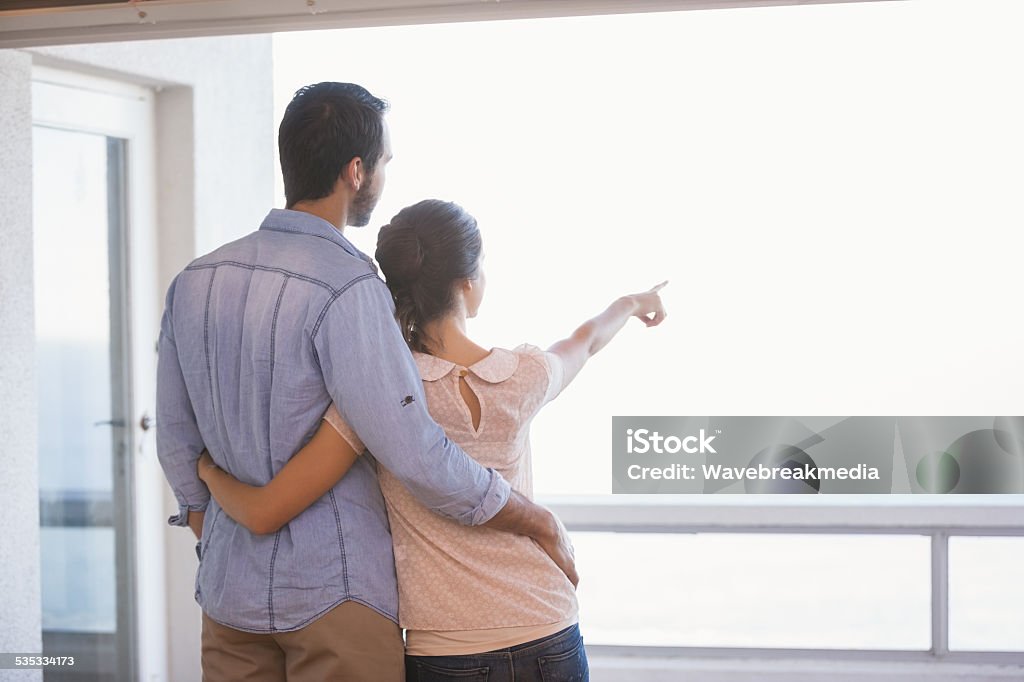 Cute couple looking out the window Cute couple looking out the window in their new home Couple - Relationship Stock Photo