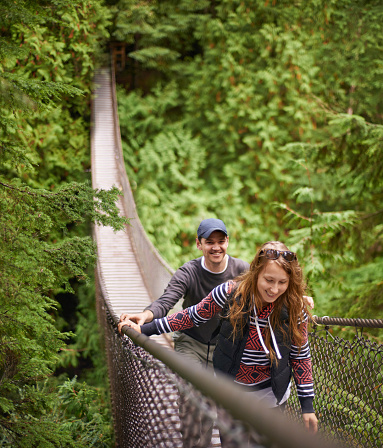 Shot of a young couple walking across a bridge in a natural forest