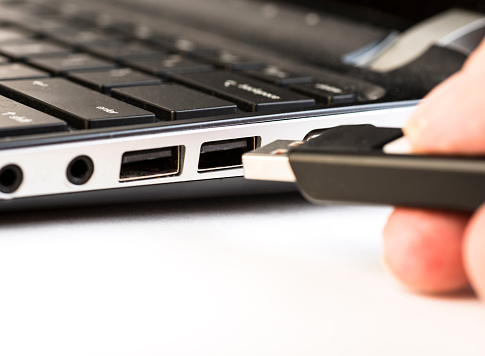 Hand held flash drive being inserted into a usb port on a laptop comuter