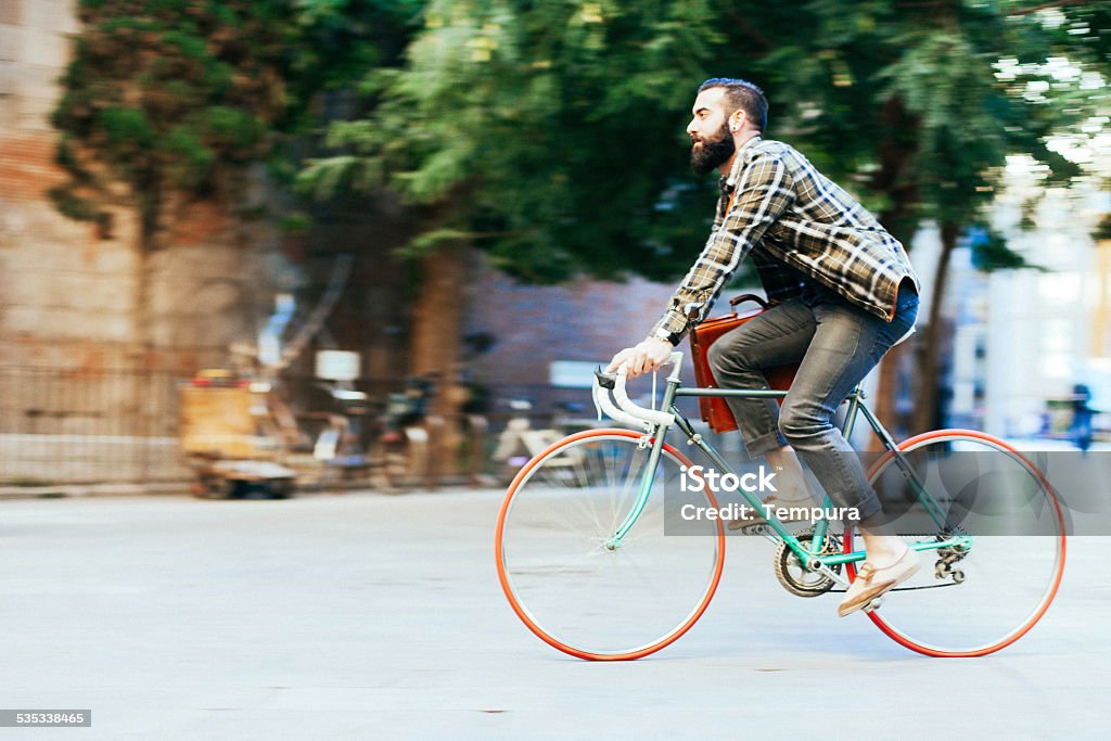 Young hipster man speeding with his bike. More files of this series on port. One young man speeding with his bike and commuting to work in the street of Barcelona. Bicycle Stock Photo